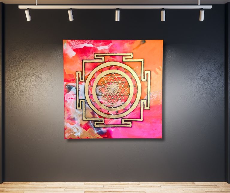 Buntes Kunstwerk mit goldenem Sri Yantra Symbol in der Mitte, an einer dunklen Wand in einem modernen Raum mit Holzfußboden und Deckenstrahlern aufgehängt.